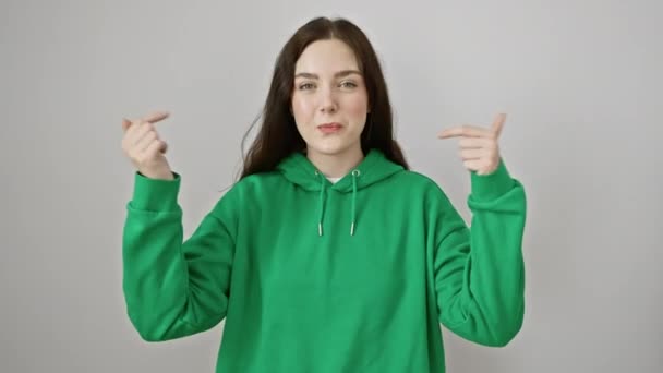美しい若い女性 スウェットシャツを着て 積極的に自信と喜びでビーム 誇らしげに指で自分を指さしている 白い背景で孤立した 広告のための完全な概念 — ストック動画