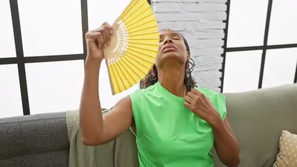 Африканская Женщина Держит Вентилятор Помещении Прохладной Зеленой Рубашкой Элегантными Серьгами — стоковое видео