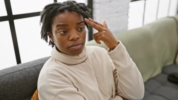 ドレッドロック 深刻な自殺ジェスチャーの屋内自宅の肖像画を描いた若い黒人女性 居心地の良いソファーに座って 頭に銃のような指を向け 耐え難いストレスとうつ病を表現する — ストック動画