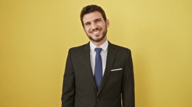 Yüzünde mutlu ve havalı bir gülümseme olan takım elbiseli İspanyol genç adam. Şanslı insan. izole edilmiş sarı arkaplan