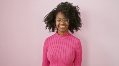 Neşeli Afro-Amerikalı kadın canlı pembe bir arka plana karşı duruyor.