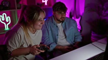 Genç bir erkek ve kadın, modern bir ev ortamında boş vakit ve arkadaşlık tasvir ederek neon ışıklı bir odada oyun oynamaktan zevk alıyorlar..