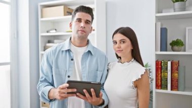 Ofiste bir adam ve bir kadın, modern bir iş yerinde takım çalışması tasvir eden bir tabletle etkileşim halindeler..