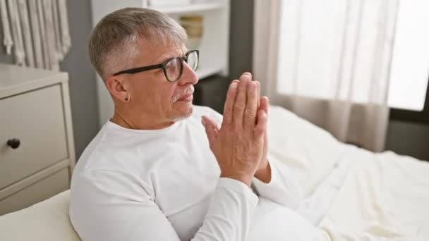 有信心的中年白发男人谦恭地请求原谅 双手紧握在他那简朴的卧室里祈祷 — 图库视频影像