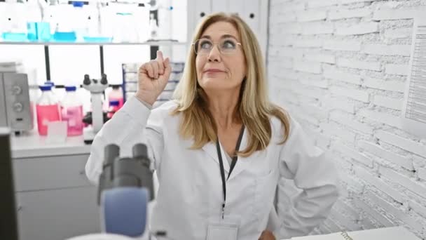 금발의 과학자는 성공적인 아이디어를 쾌활하게 손가락을 가리키는 실험실에서 — 비디오
