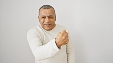 Öfkeli, orta yaşlı, hırkalı, öfkeli Latin bir adam! Tek başına duruyor, çılgınca bağırıyor, yüzü beyaz arka planda bir hayal kırıklığının portresi gibi.