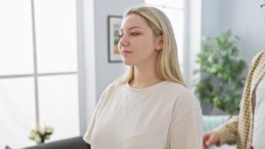 Bir erkek, sıcak bir oturma odasında, sevgi ve neşe ifade eden gözbağı ile bir kadını şaşırtır..