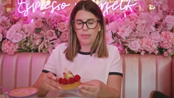 Молода Жінка Насолоджується Пирогом Квітковому Рожевому Кафе Втілюючи Індульгенцію Насолоду — стокове відео