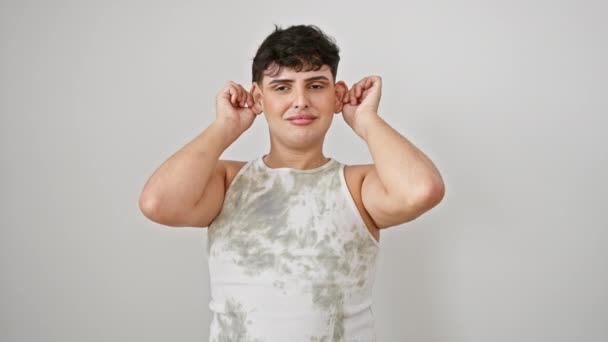 陽気な若い男が面白い顔を作り 袖のないTシャツを着て 耳を引っ張り 白い隔離された背景の上に漫画のオーディションスタント — ストック動画