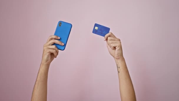 ピンクの背景にスマートフォンとクレジットカードを持ち オンライン決済やショッピングを提案 — ストック動画