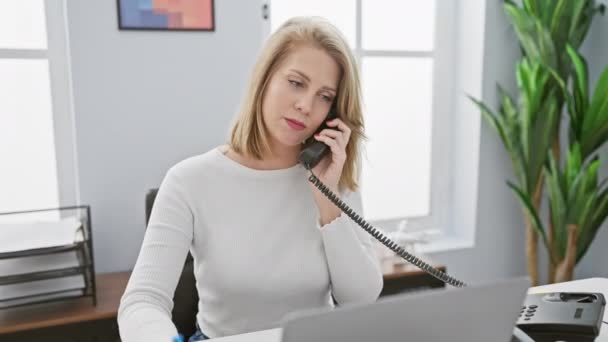 一位忧心忡忡的金发女人在一间现代化的办公室打电话时 正在检查药物 — 图库视频影像