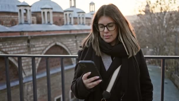 Молодая Женщина Использует Смартфон Мосту Стамбуле Закате Демонстрируя Технологии Путешествия — стоковое видео