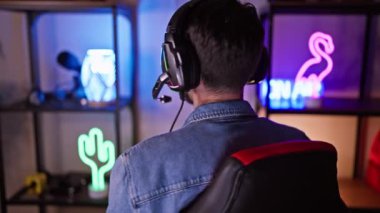 Odaklanmış genç bir İspanyol 'un portresi. Canlı bir oyun odasında gece kulaklık takıyor..