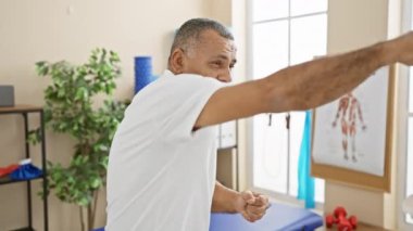 Orta yaşlı bir İspanyol, bir rehabilitasyon kliniğinin iç kısımlarında sağlık ve refahı desteklemek için egzersiz yapıyor..