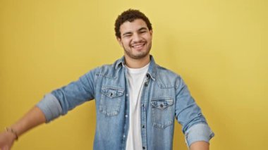 Keyifli genç bir Arap erkeği elleri ve parmaklarıyla bir çerçeveyi cesurca şekillendirir, canlı sarı izole bir arka plana yaratıcılık ve fotoğraf konseptini hayat verir.