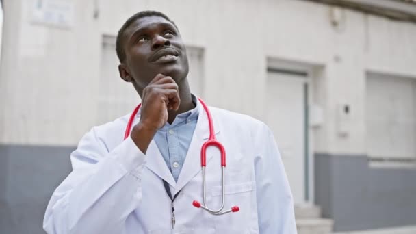 Homme Africain Réfléchi Dans Manteau Médecin Avec Stéthoscope Tient Devant — Video