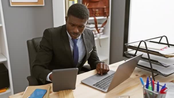 专注于商务服装的非洲男人在写字台的笔记本电脑上工作 带着智能手机和用品 — 图库视频影像