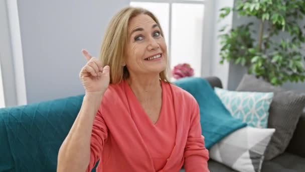 Fröhliche Blondine Mittleren Alters Sitzt Hause Auf Ihrem Gemütlichen Sofa — Stockvideo