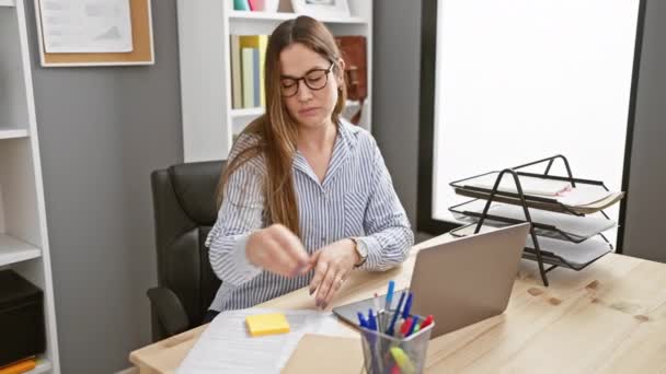 안경을 집중된 여성은 노트북과 문구가있는 깔끔한 사무실 책상에서 문서를 검토합니다 — 비디오