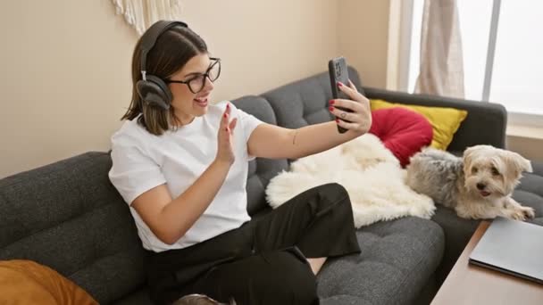Wesoła Młoda Kobieta Słuchawkach Używa Smartfona Rozmowy Wideo Jej Przytulnym — Wideo stockowe