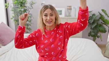 Kırmızı pijamalı neşeli orta yaşlı bir kadın. Kalpleri yatak odasında mutlu bir şekilde uzanıyor. Evdeki rahatlık ve neşeyi temsil ediyor..