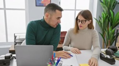 Kadın ve erkek, masadaki dizüstü bilgisayar, gözlük ve kırtasiye malzemeleriyle parlak bir ofiste ciddi ciddi sohbet ediyorlar..