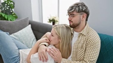 Sevgi dolu bir çift, rahat bir oturma odasında kanepede sarılıp, bir erkekle bir kadını evlerinde barışçıl ve sevgi dolu bir anın tadını çıkarıyorlar..