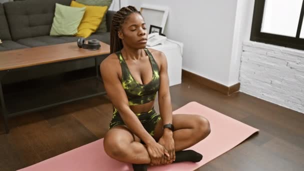 Afroamerikanerin Mit Zöpfen Trainingskleidung Meditiert Einem Modernen Wohnzimmer Auf Einer — Stockvideo