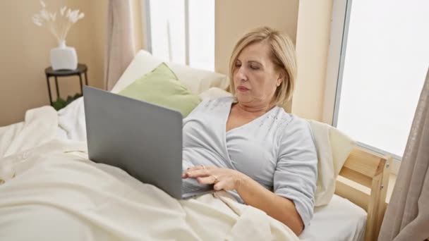 Ältere Blonde Frau Mit Laptop Schlafzimmer Darstellung Der Alltäglichen Nutzung — Stockvideo