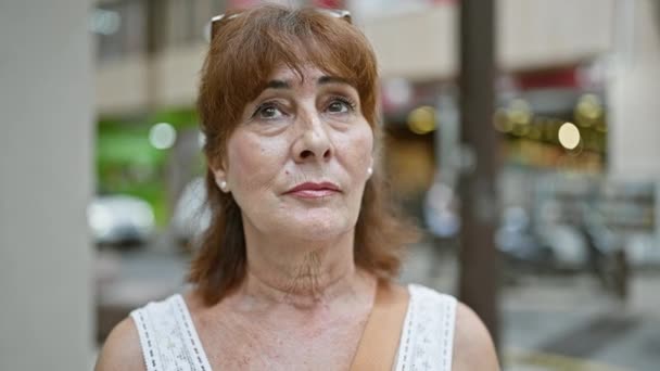 Mujer Pelirroja Madura Con Expresión Contemplativa Pie Una Calle Ajetreada — Vídeos de Stock