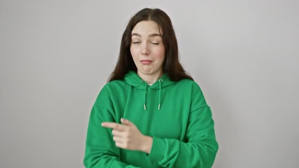 スウェットシャツを着た若い女性が驚きの表情で指摘 開いた口 隔離された白い背景に対する側面への指 ジョギング サプライズ — ストック動画