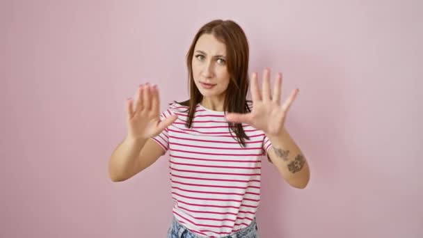怒气冲冲的年轻的黑发女孩穿着条纹T恤 用停止的动作表达沮丧 双手放在粉色孤立的背景上 — 图库视频影像