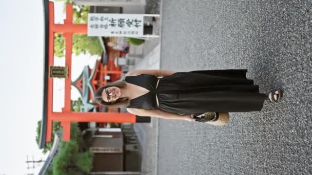 ヒスパニック系の女性を魅了し メガネでビームの笑顔を浮かべ 京都の象徴的な稲荷大社でカメラに向かって気軽にポーズをとり歩いた — ストック動画