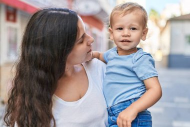 Anne ve oğlu sokakta kendinden emin gülümsüyor.