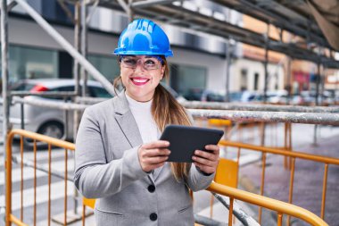 Genç, güzel İspanyol bir mimar sokakta dokunmatik ped kullanarak gülümsüyor.