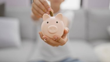 Sevimli sarışın çocuk evdeki kanepede dinlenirken kumbarasına rahatça para yatırıyor ve bir çocuğun hayat tarzına yatırım ve finans dersleri veriyor..