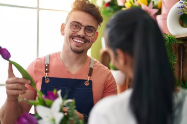 Çiçekçi dükkanında çalışan bir buket çiçek tutan erkek ve kadın.