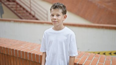 Şirin küçük sarışın çocuğun ciddi yüzü şehrin caddesinde dimdik duruyor, sevimli çocuğun şehir geçmişine bakan yoğun ifadesi.