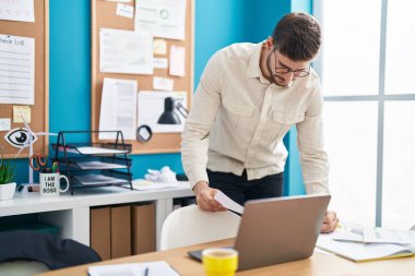 Genç Kafkasyalı iş adamı ofisteki belgede dizüstü bilgisayarla yazı yazıyor.