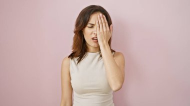 Pembe bir duvarın karşısında bir gözünü kapayan stresli genç bir kadının portresi hayal kırıklığı ya da baş ağrısı gösteriyor..