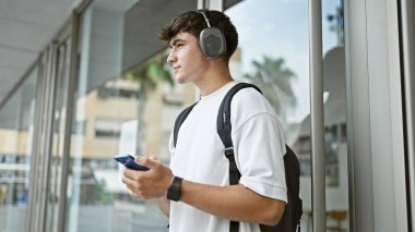 Havalı, genç bir İspanyol, ciddi bir üniversite öğrencisi, akıllı telefonuyla müzik dinliyor, şehir kampüsünün ortasında kendini kaybetmiş..