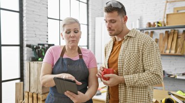 Bir kadın ve bir erkek, marangozluk aletleriyle çevrili bir tablet üzerinde tartışıyorlar..