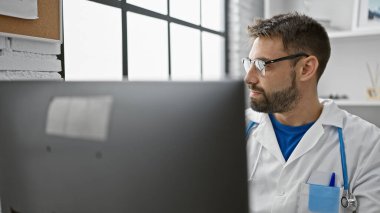 Genç İspanyol doktor bilgisayar kullanıyor. Kliniğe bakıyor.