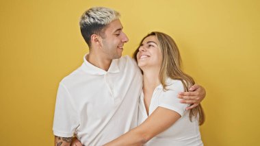 Güzel bir çift gülümsüyor. Birbirlerine sarılıyorlar ve izole edilmiş sarı arka planda birbirlerine bakıyorlar.