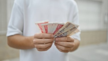 Genç, yakışıklı İspanyol genç. Kentsel bir caddede banknotları sayıyor. Finans ve yatırımı araştırıyor.