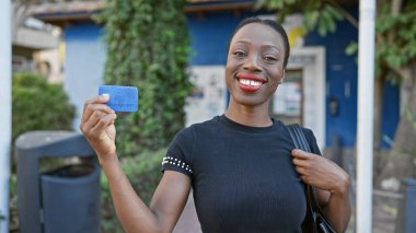 Kendine güvenen Afro-Amerikan kadını, mutluluk saçan, kredi kartını işlek bir şehir caddesinde sergileyen, maddi özgürlüğü ve bağımsız bir yaşam tarzının neşesini somutlaştıran,.