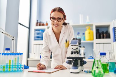 Genç beyaz kadın bilim adamı laboratuarda çalışıyor.