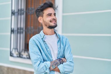 Sokakta kollarını kavuşturmuş İspanyol genç bir adam.