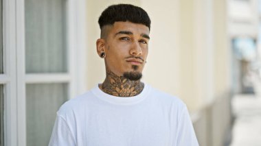 Sokakta ciddi bir ifadeyle dikilen genç Latin adam.