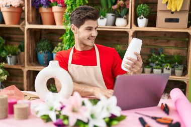 Çiçekçide dizüstü bilgisayar kullanan İspanyol bir çiçekçi.